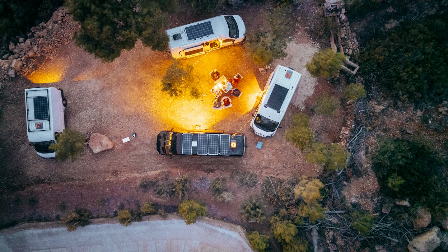 Wohnmobile in der Nähe eines Lagerfeuers in der Dämmerung.